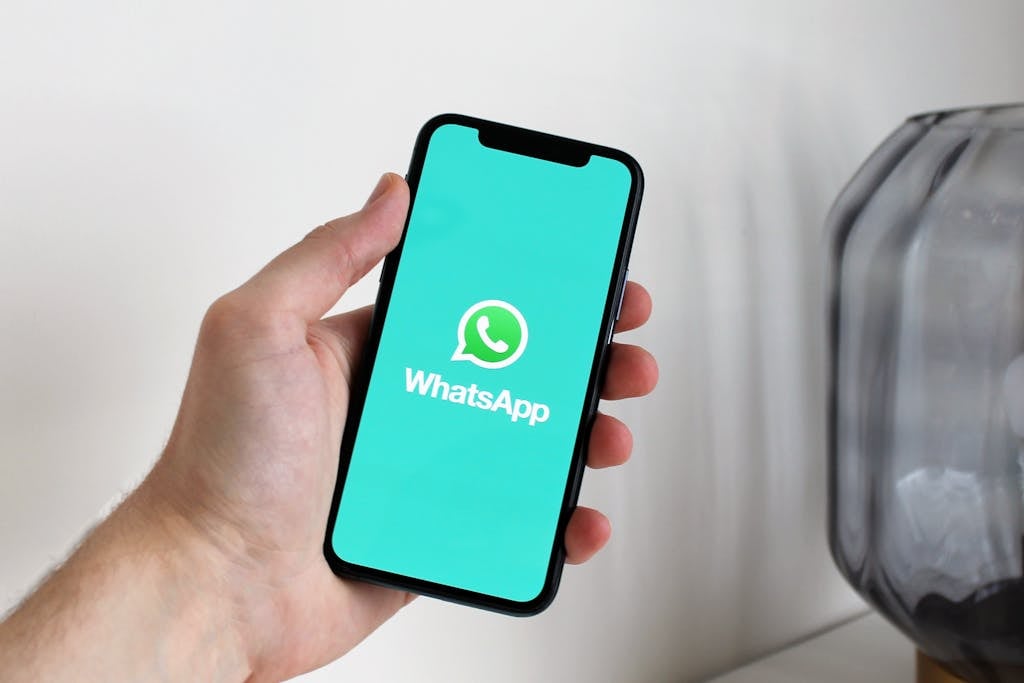 Primer plano de una mano sosteniendo un teléfono inteligente que muestra la pantalla de la aplicación de WhatsApp.