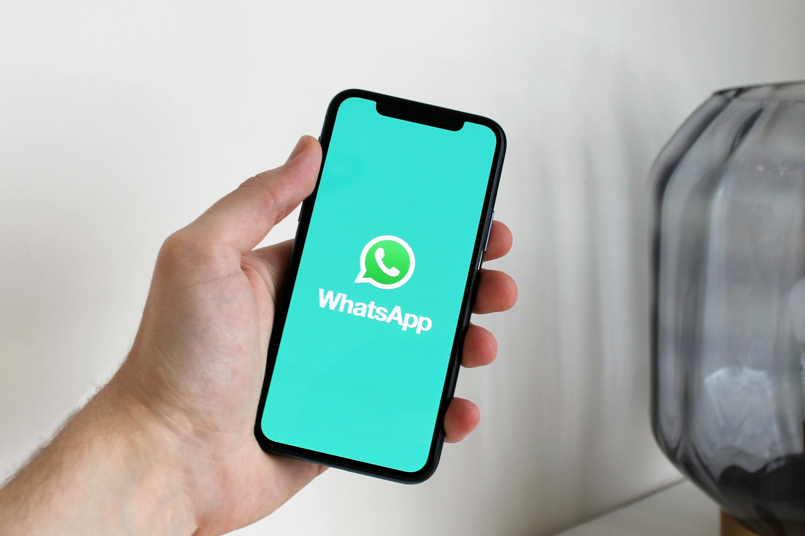 Primer plano de una mano sosteniendo un teléfono inteligente que muestra la pantalla de la aplicación de WhatsApp.